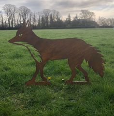 a metal sculpture of a wolf in the grass