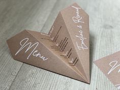 three folded brown paper cards with white writing on them