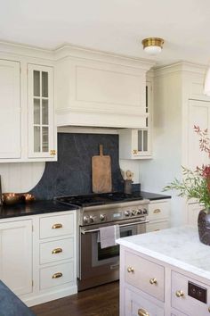 a kitchen with white cabinets and marble counter tops, an island in front of the stove