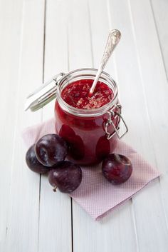 a jar filled with plum jam sitting on top of a pink napkin