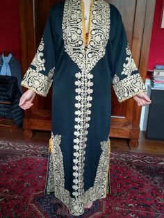 This is a handmade Syrian Aghabani dress, featuring intricate gold embroidery on rich black fabric. The design showcases traditional motifs, with detailed patterns along the sleeves, neckline, and hem, making it a stunning example of Syrian craftsmanship. Perfect for special occasions, the luxurious embroidery elevates its elegance and cultural significance. Measurements: - Armpit to armpit: 60 cm - Length: 135cm A beautiful piece that showcases the artistry and tradition of Syrian craftsmanship Gold Embroidered Festive Dress, Elegant Gold Dress With Resham Embroidery, Traditional Gold Embroidered Dress With Resham Embroidery, Festive Gold Embroidered Dress, Ceremonial Traditional Embroidered Dress, Gold Kurta With Dabka Work For Traditional Ceremonies, Traditional Gold Embroidered Festive Dress, Gold Dress With Intricate Embroidery For Traditional Ceremonies, Elegant Gold Embroidered Dress For Eid