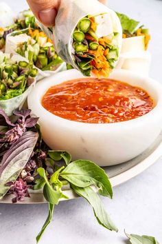 a person dipping sauce into a bowl of salad