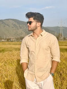 a man standing in the middle of a field with his hands in his pockets and looking off into the distance