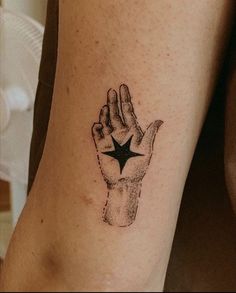 a person with a tattoo on their arm holding up a star in the middle of his hand