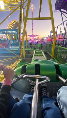 a person riding on the back of a green and yellow roller coaster at an amusement park