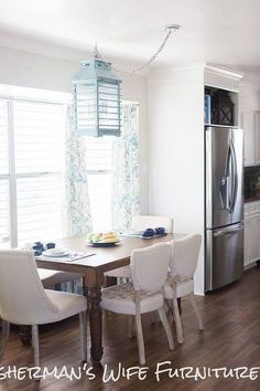 a kitchen table with four chairs and a refrigerator in the back drop off window behind it