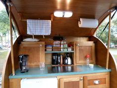 the inside of a camper with wooden cabinets and blue counter tops, including a coffee maker