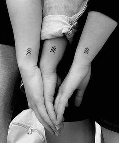 two people with matching tattoos on their arms holding hands and touching each other's fingers