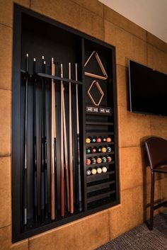 a wall mounted billiards rack with pool cues and cues in front of a flat screen tv