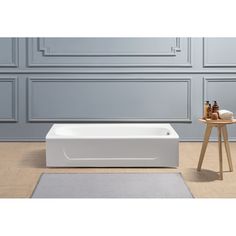 a white bath tub sitting on top of a floor next to a wooden table and chair