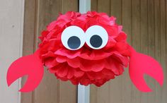 a red paper ball with googly eyes hanging from the side of a wooden door