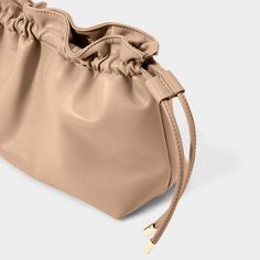 Discover the latest addition to the Katie Loxton family - the Hailey Crossbody Clutch in soft tan! This versatile bag offers you two stylish ways to wear it - either as a trendy crossbody for an effortless day look or as an elegant clutch to elevate any evening outfit. With its drawstring closure detail, vegan leather material, and gleaming gold-tone hardware, this bag exudes understated luxury and attention to detail. Sure to become a staple in your wardrobe, and a piece you can rely on for yea Versatile Taupe Crossbody Bag, Versatile Pouch Shoulder Bag For Spring, Versatile Taupe Shoulder Bag, Beige Pouch Shoulder Bag For Day Out, Versatile Neutral Bag With Adjustable Strap, Versatile Pouch Bag For Spring, Chic Taupe Bags For Fall, Casual Taupe Crossbody Bag, Versatile Solid Color Spring Bags