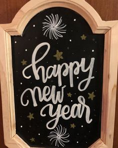 a sign that says happy new year written in white paint on a black background with fireworks