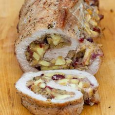 a sliced loaf of meat on a cutting board with cranberry sauce and pineapple toppings