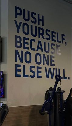 a woman is standing in front of a wall that says push yourself because no one else will