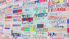 a wall covered with lots of different types of writing on it's sides and words written in large, multicolored letters