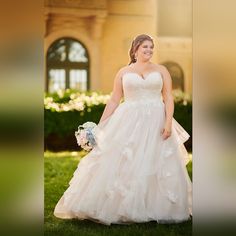 a woman in a wedding dress is standing on the grass and smiling at the camera