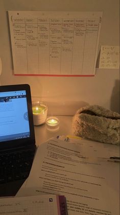 an open laptop computer sitting on top of a desk next to a pile of papers