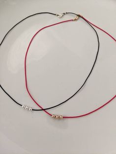 two red and black cord necklaces on a white plate