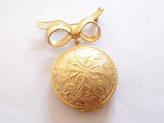 This vintage 70's Avon Perfume gold tone brooch, signed Avon products New York. It opens with a secure hinged clasp on the locket area to reveal solid perfume. This area has a diameter of 1.25 inches/3.2cm. The whole brooch fastens with a secure roll lock safety clasp & has a length of 9.6 inches/25.3cm and a width of 1.41 inches/3.6cm. A beautiful locket to wear, and it has a lovely perfume to rub, along you neck or wrist. Locket will be wrapped & place in a gift box. *SHIPPING* US ORDERS-ship through the USPS First Class, shipping takes 2-5  business days with delivery confirmation.  INTERNATIONAL ORDERS are shipped through the USPS International First Class, shipping time is 2-4 weeks depending on location. If you have any questions please send me a convo, I will reply as soon as possib Vintage Medallion Brooch For Wedding, Vintage Medallion Brooches For Wedding, Gold Locket Brooch For Collectors, Gold Locket Brooches For Gifts, Gold Brooches With Vintage Charm For Gift, Gold Brooches With Vintage Charm As Gift, Gold Medallion Brooch For Formal Occasions, Vintage Medallion Brooches For Formal Occasion, Gold Medallion Brooch For Gift