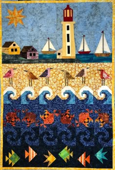 a quilted wall hanging with sailboats and lighthouses on the water in front of an ocean