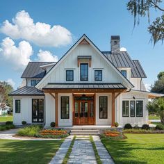 a white house with a black roof and two story windows on the second floor is surrounded by lush green grass