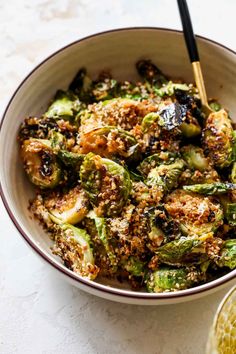 a white bowl filled with cooked brussel sprouts and topped with breadcrumbs