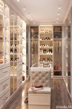 a walk in closet filled with lots of white shelves and shoes on top of them