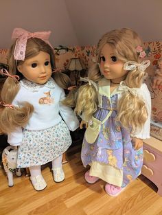 two dolls standing next to each other on a wooden floor