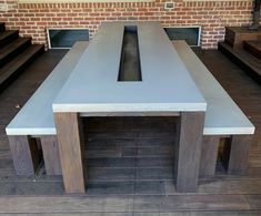 an outdoor table made out of concrete and wood with stairs leading up to the top