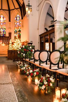 rows of chairs with flowers and candles on them in front of the alter at a church