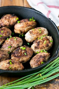 cooked meatballs in a skillet with chives on the side, ready to be eaten