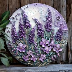 a plate with purple flowers painted on the side of it and greenery behind it