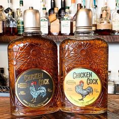 two bottles of chicken cook sitting on top of a wooden table next to each other