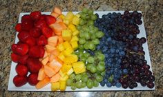 a platter filled with grapes, strawberries, and melon on top of a marble counter