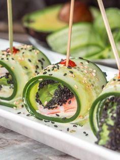 cucumber rolls with black sesame seeds and ketchup on a white plate