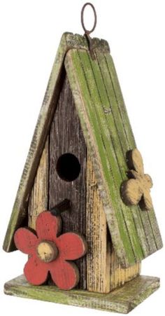 a birdhouse with flowers on the roof and one flower hanging from it's side