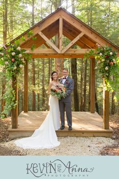 a bride and groom standing in front of a gazebo with flowers on it at their wedding