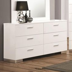 a white dresser with a black lamp on top of it and a mirror above it