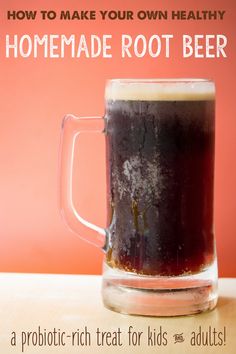 a glass mug filled with root beer sitting on top of a table next to an orange wall