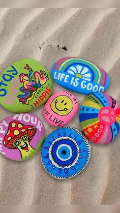 there are many different colored rocks on the beach with words and pictures painted on them