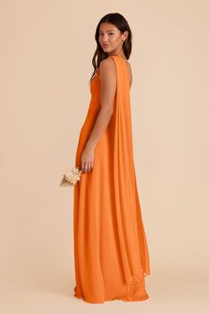 a woman in an orange dress is standing with her hands on her hips and looking off to the side