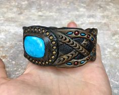 "\"Past and future secrets\" is a tooled leather bracelet with bright blue Arizona turquoise cabochon. Nice piece of jewelry for a stylish man. The bracelet is 1 1/2\" (~4cm) in widest place and fits up to ~8\" (~20cm) wrist. This particular bracelet was MADE TO ORDER. If you would like to get something similar (or something different) - just place a custom order and I will arrange something for you. Please bear in mind I can't repeat the same precise design since each item I make is unique. Thu Southwestern Leather Bracelet As Gift, Southwestern Style Leather Bracelets As Gift, Southwestern Style Leather Bracelet As Gift, Handmade Turquoise Leather Cuff Bracelet, Southwestern Leather Bracelet As A Gift, Unique Concho Leather Bracelet Gift, Unique Leather Concho Bracelet For Gift, Turquoise Leather Bracelet, Mens Cuff Bracelets