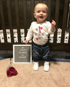 a baby standing in front of a sign that says my 1 valentine's day