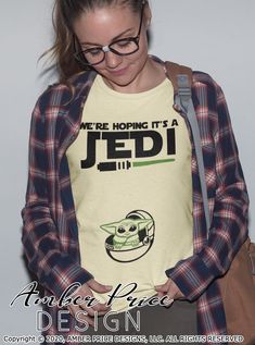 a woman wearing a star wars t - shirt with the words, we're hoping it's a jedi