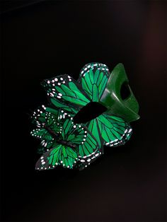 This striking handmade mask features intricate emerald green butterfly wings adorned with delicate white accents, creating a captivating whimsical look. Perfect for masquerade balls, costume parties, or any special occasion, the Emerald Butterfly Masquerade enhances your ensemble with its unique charm. Age Group/Gender - Adult/Women Size/Type - One size fits all adults Mask Color - Emerald Green Butterfly Color - Emerald Green Mask Material - polyresin Accent Material - butterflies made of feath