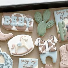 decorated cookies in the shape of baby's clothes and booties are on display