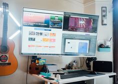 a computer monitor sitting on top of a desk next to a guitar