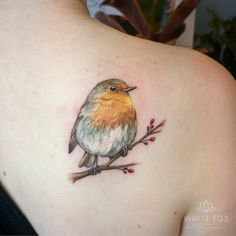 a small bird tattoo on the back of a woman's shoulder