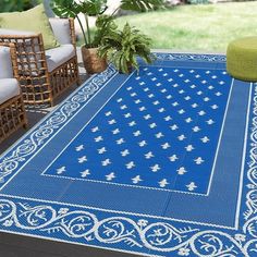 a blue rug on a patio with wicker chairs and potted plants in the background